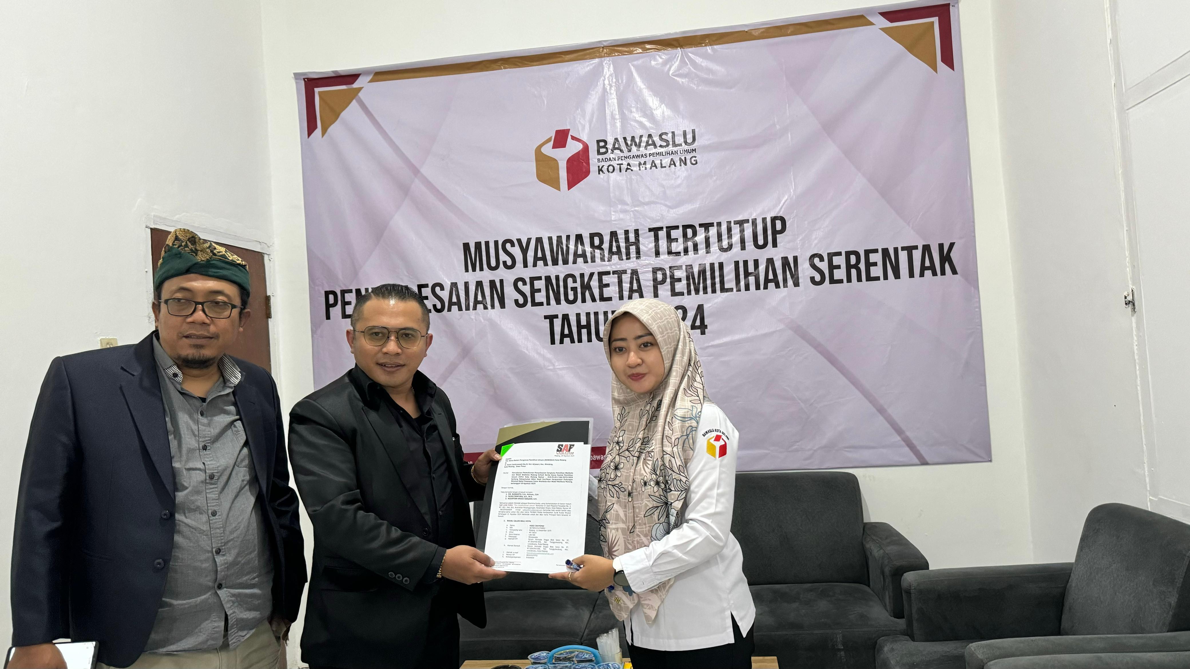 Ria Amelia (Kanan), Staf Teknis Divisi Hukum dan Penyelesaian Sengketa menerima surat pernyataan pencabutan permohonan sengketa pemilihan serentak 2024 di Kantor Bawaslu Kota Malang, hari ini (28/08).